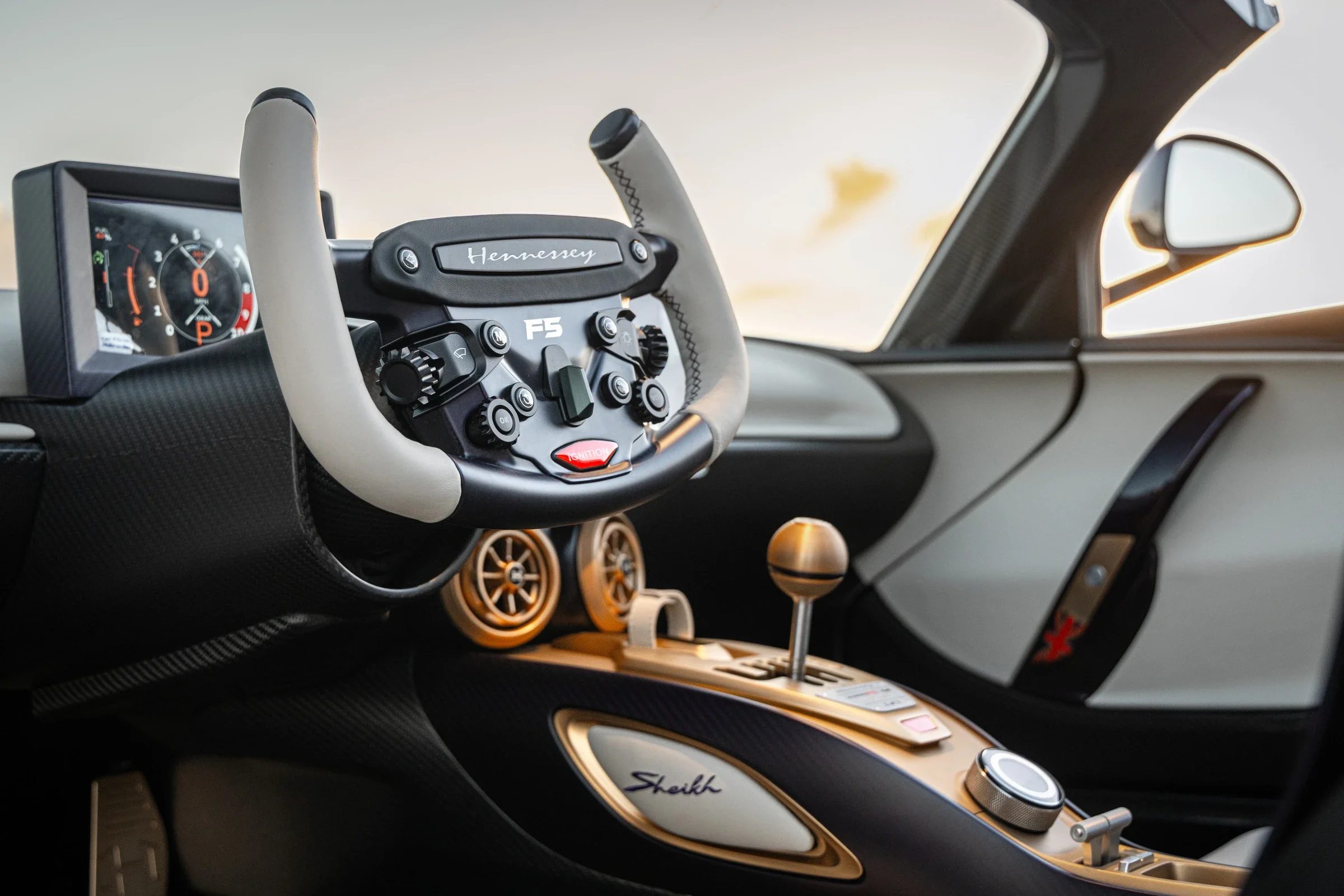 Fahrerorientiertes Cockpit des Hennessey Venom F5-M mit Carbon und goldenen Bedienelementen